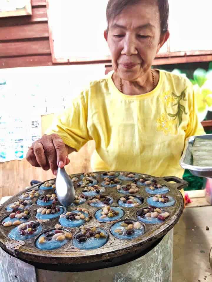 Sukhothai woman is cooking Kanom Krok with butterfly pea flowers coloring