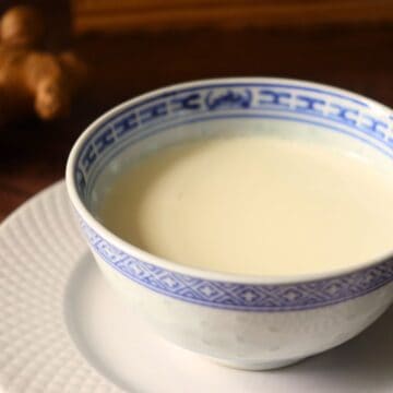 ginger milk curd in a chinese bowl on a plate with fresh ginger behind